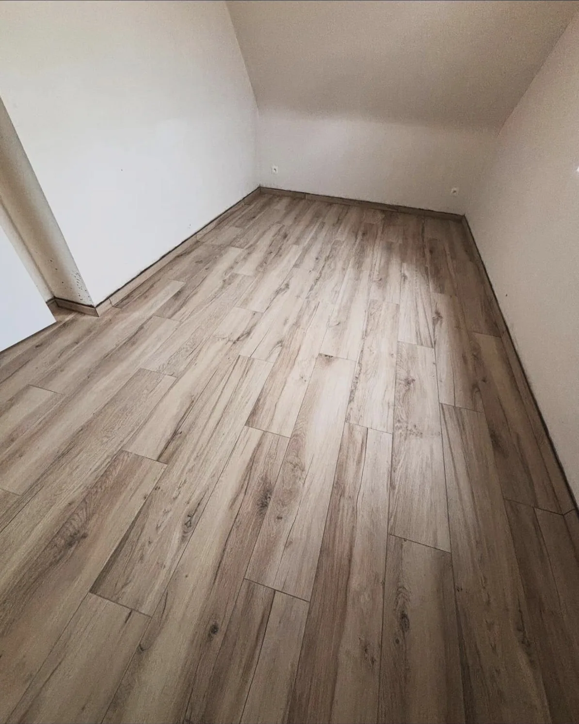 Pose du carrelage effet bois dans une pièce sous combles