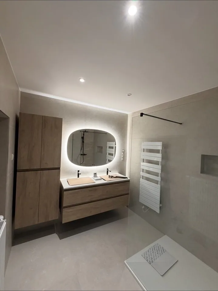 Salle de bain beige avec miroir ovale rétroéclairé