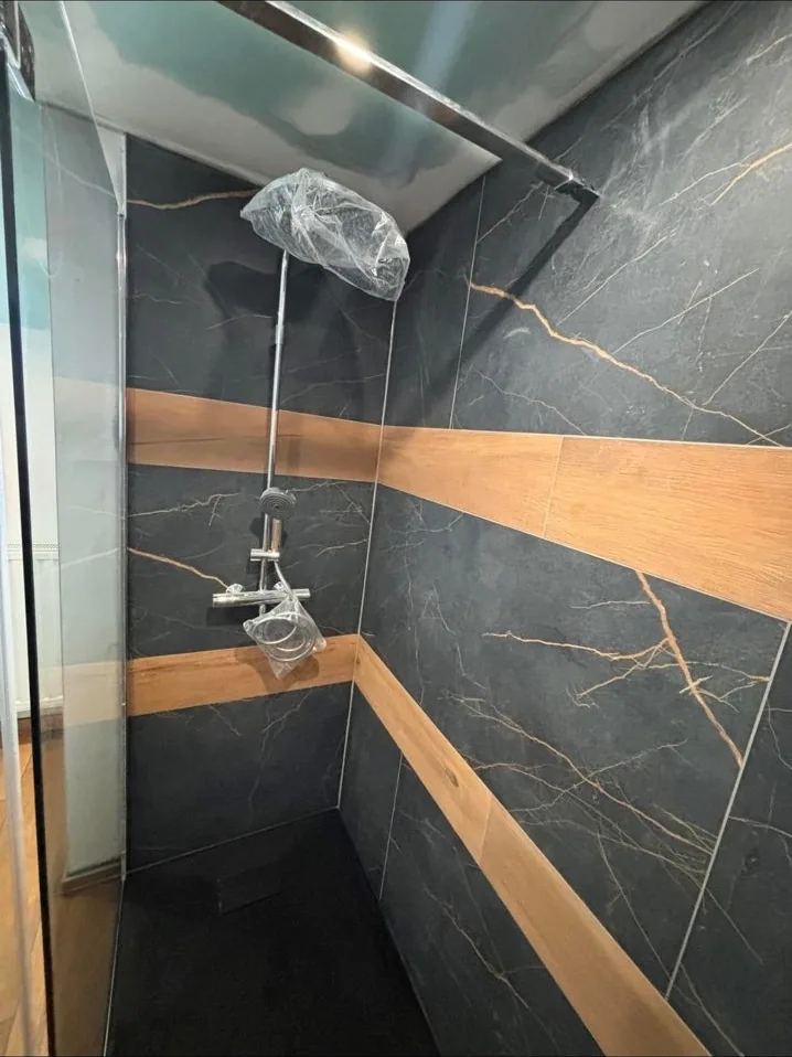 Douche en carrelage effet marbre noir avec bandeau bois