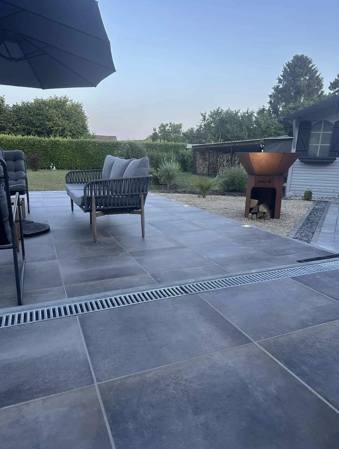 Terrasse grand format avec salon extérieur et brasero