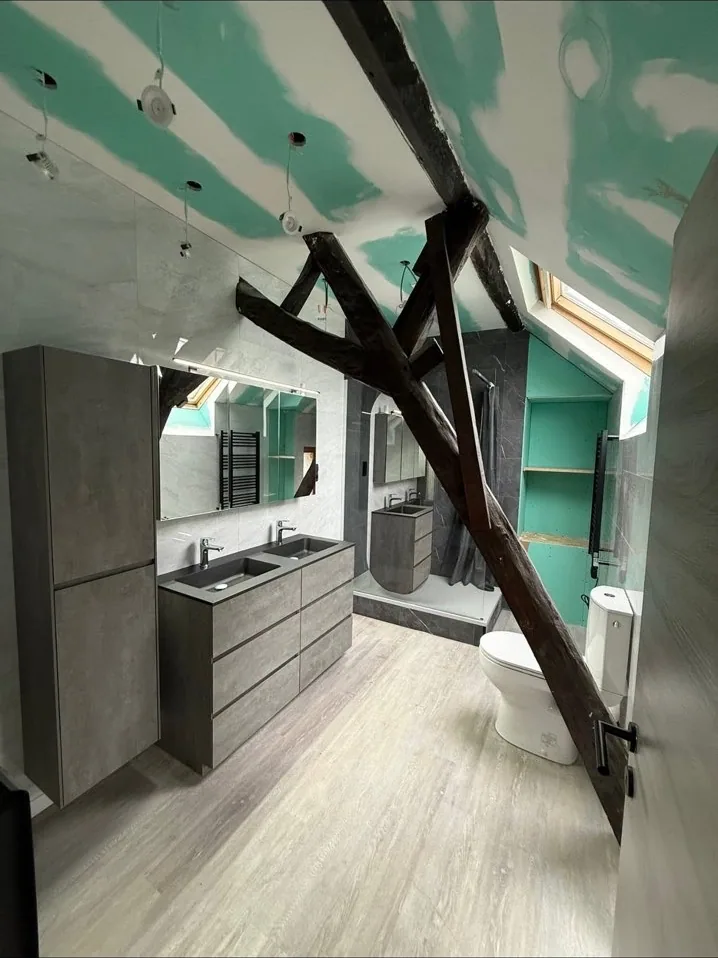 Salle de bain sous combles avec poutres apparentes et miroirs