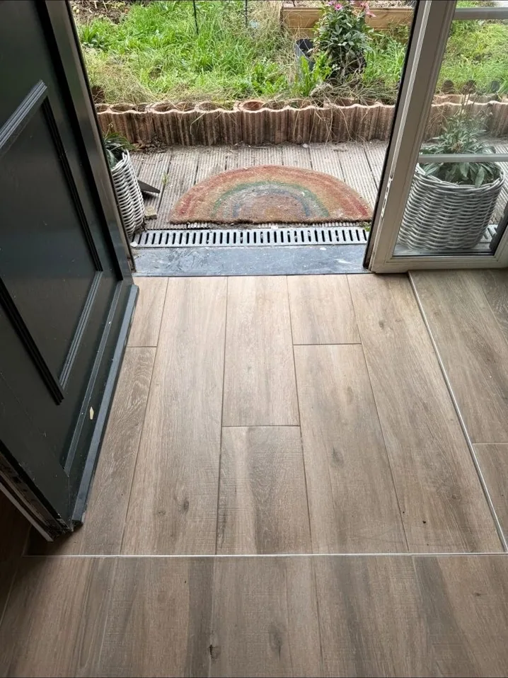 Pièce de vie rénovée avec carrelage effet bois et grande baie