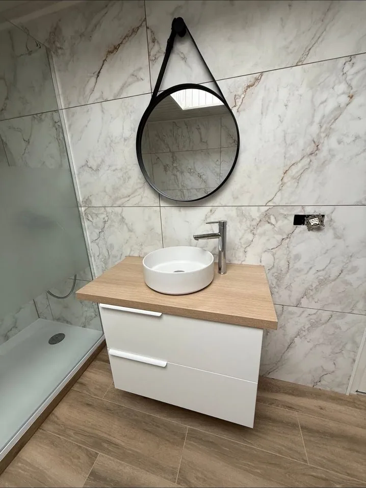 Meuble vasque suspendu et miroir rond dans la salle de bain marbre