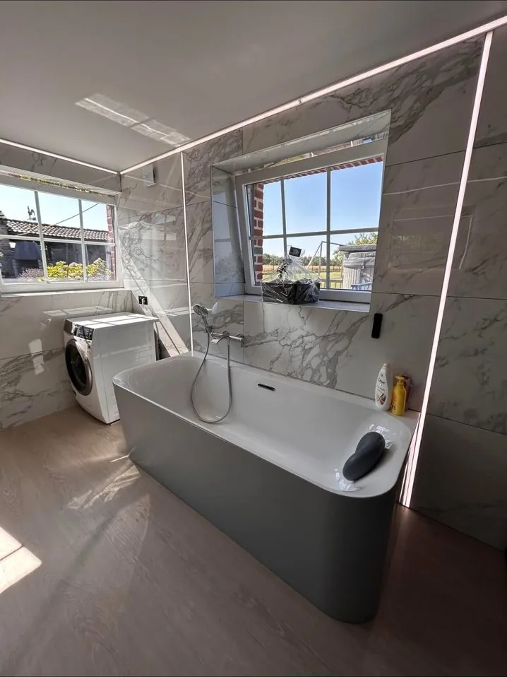 Baignoire îlot devant la baie vitrée de la salle de bain rénovée